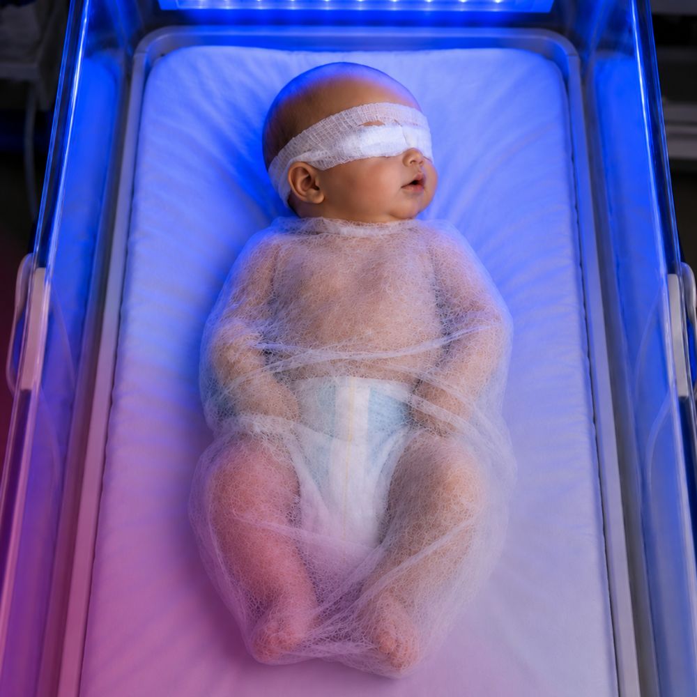 Pasgeborene in blue light wrap voor geborgenheid tijdens fototherapie